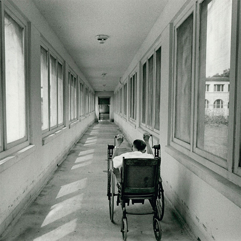 A leprosy patient wheels down a hallway.