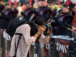 Columbia Missourian photographer Tanishka R., a graduate student studying photojournalism, takes photos of the Jefferson City High School Marching Band during pre-game ceremonies. Photo by Nate Brown | Copyright 2021 Curators of the University of Missouri