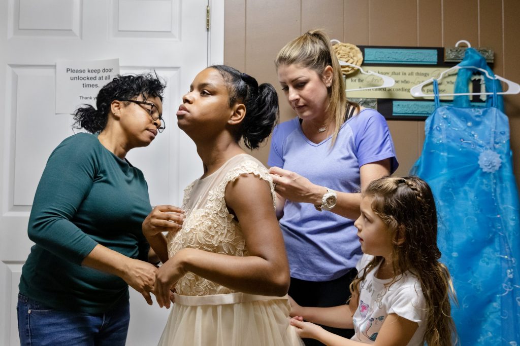 From left, Shayla's mom, Willishia Rudd, Jessica Kolle and her daughter, Kynlee, 6, help Shayla, 16, try on a dress for the Night to Shine prom event. Photo courtesy of Yehyun Kim.