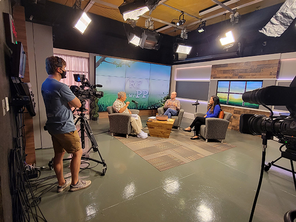 Jeb Goldman looks on as Paul Pepper interviews local dentists Philip Batson and Elizabeth Abe for a segment on his show, Radio Friends with Paul Pepper. Goldman serves as camera operator and floor director for the first three of ten shows recorded every-other Tuesday. Photo: Grace Vance