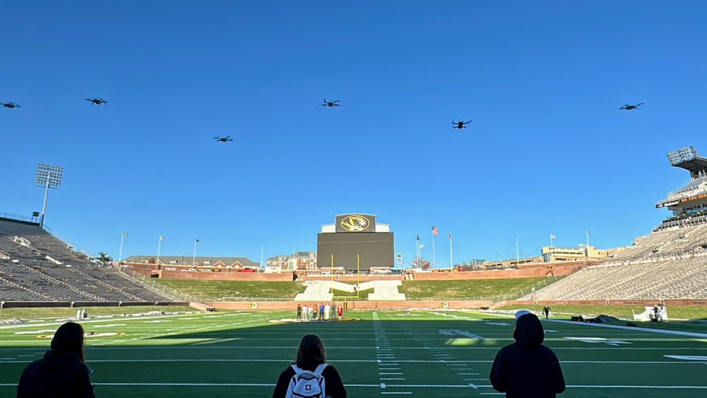 Several drones fly over Faurot Field -- and the finalists in the oval -- before the start of the Top Drone competition on Dec. 4, 2024. Photo: Nate Brown