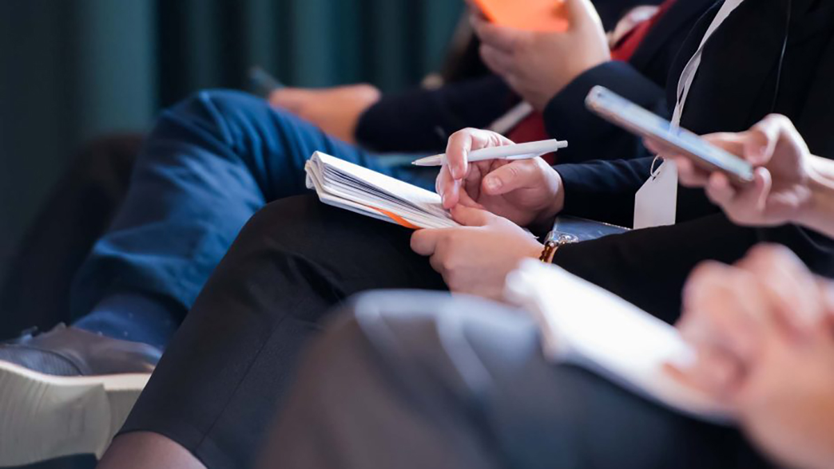 Reporters in an audience taking notes